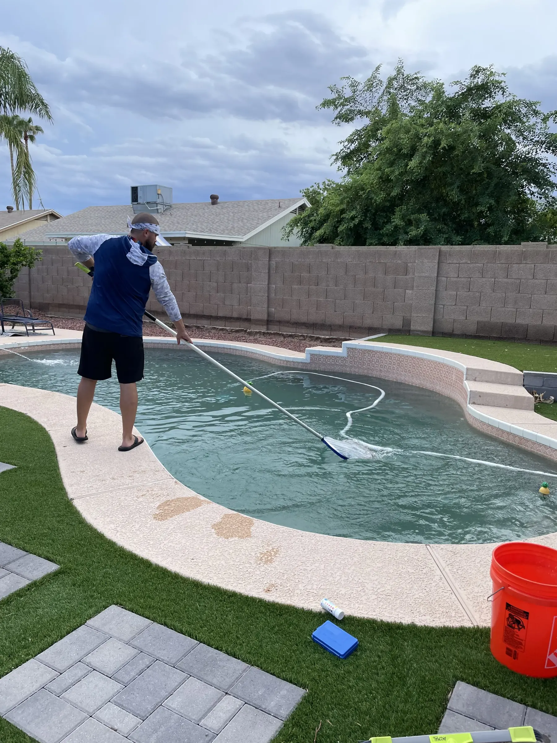 DJ, owner of Bell Road Pool Care, cleaning a residential pool